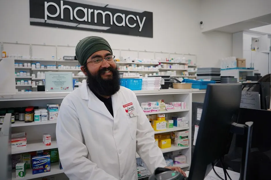 Pharmacist standing in front of shelves stocked with medicine, illustrative stock photo